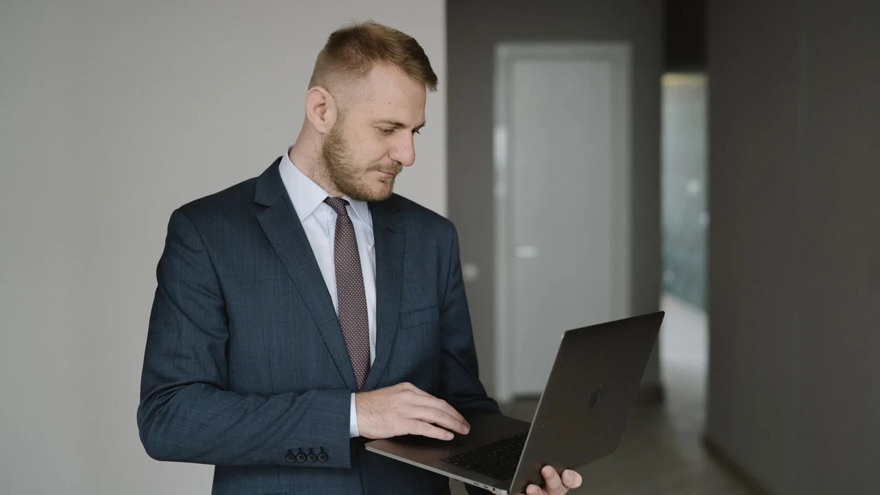 Businessman in suit works on laptop in a modern office setting, conveying professionalism.