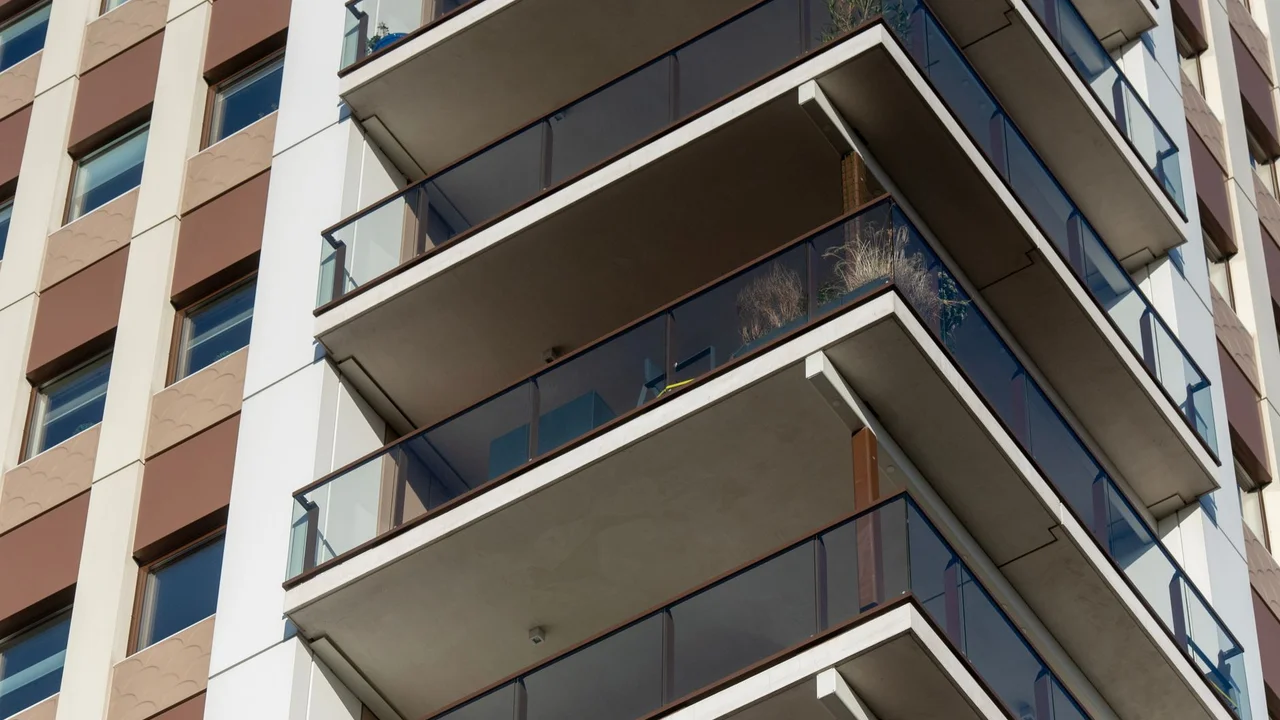 A detailed view of the balconies of a modern high-rise apartment building with glass railings.