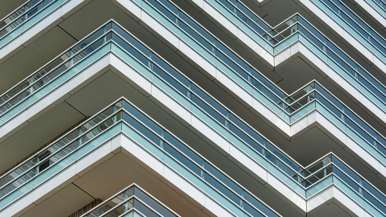 Close-up view of modern apartment building facade with glass balconies in an urban setting.