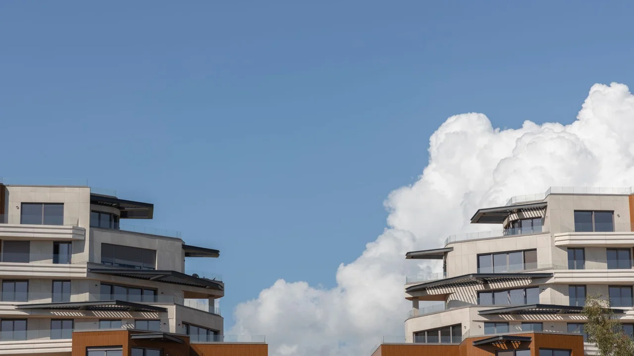 Contemporary urban architecture under a bright blue sky with clouds.