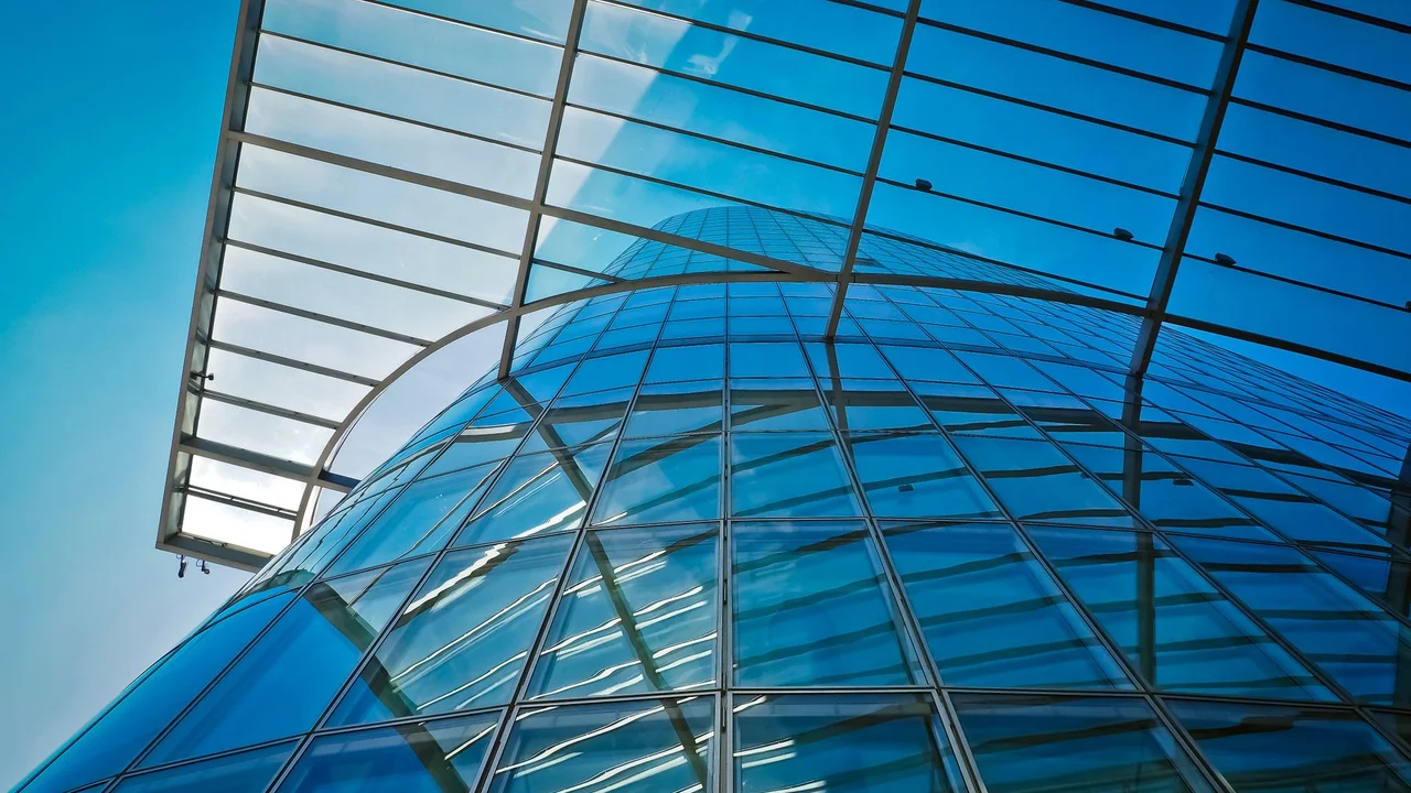 A striking view of modern glass architecture reflecting the blue sky.
