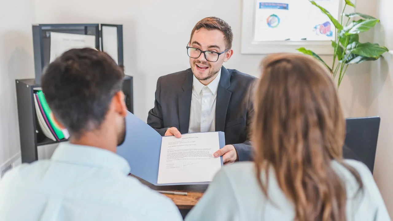 A businessman discusses a contract with clients in a modern office setting.