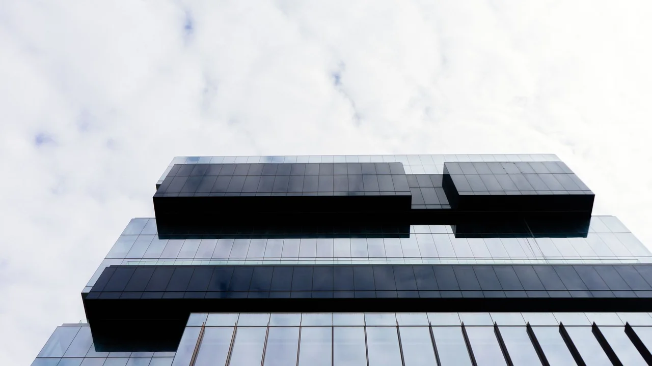 Contemporary building with a glass facade and geometric patterns, low angle view.