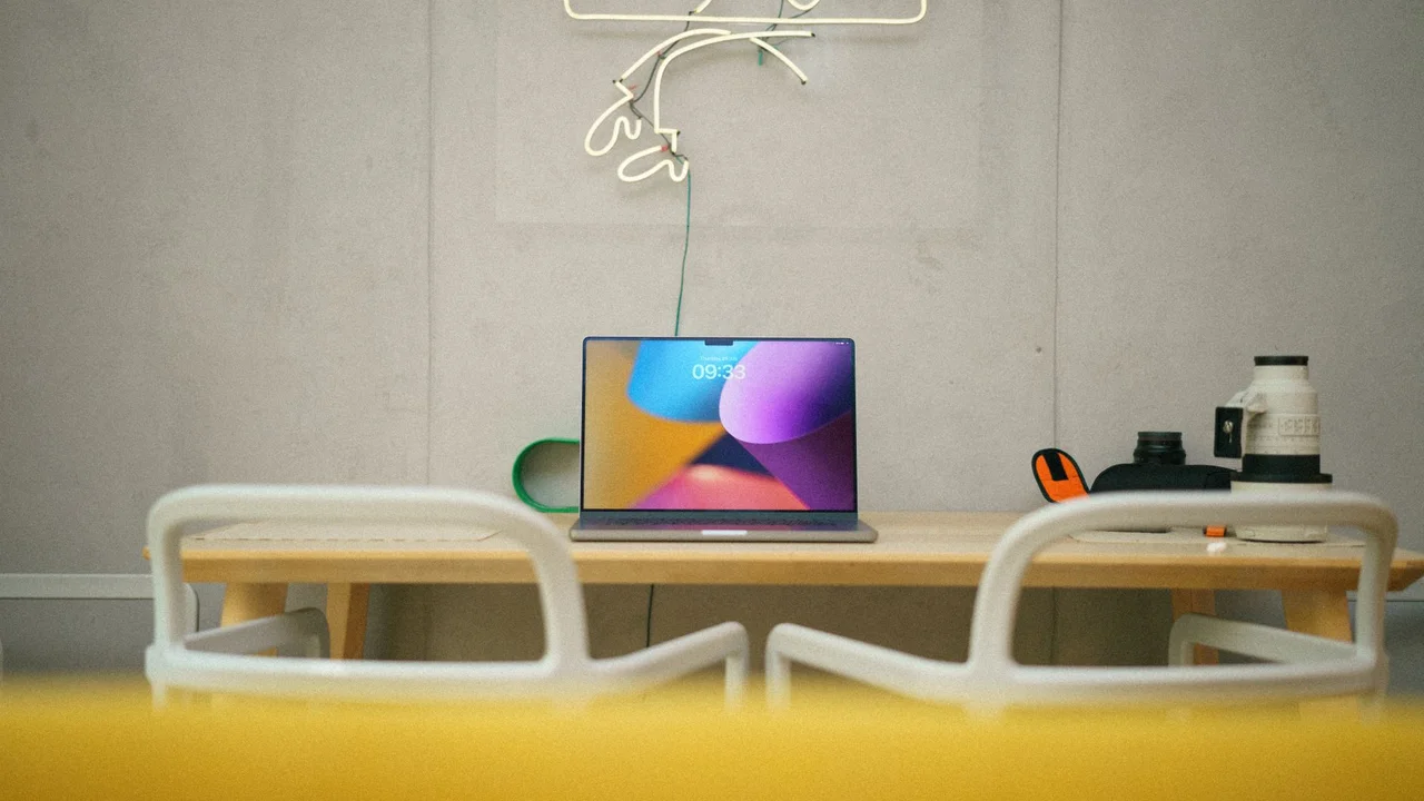 Modern home office with laptop on desk, neon art, and minimalist design.