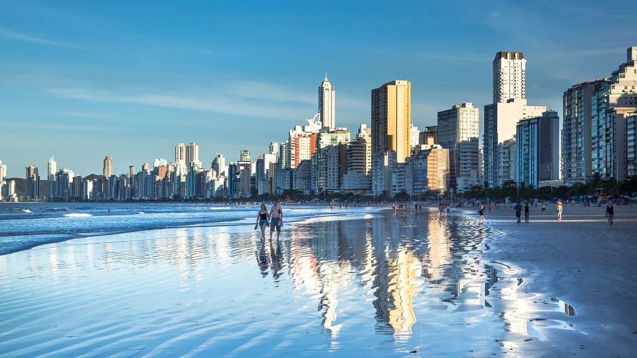 Stunning view of Balneário Camboriú's modern skyline reflecting on the beach at daytime.