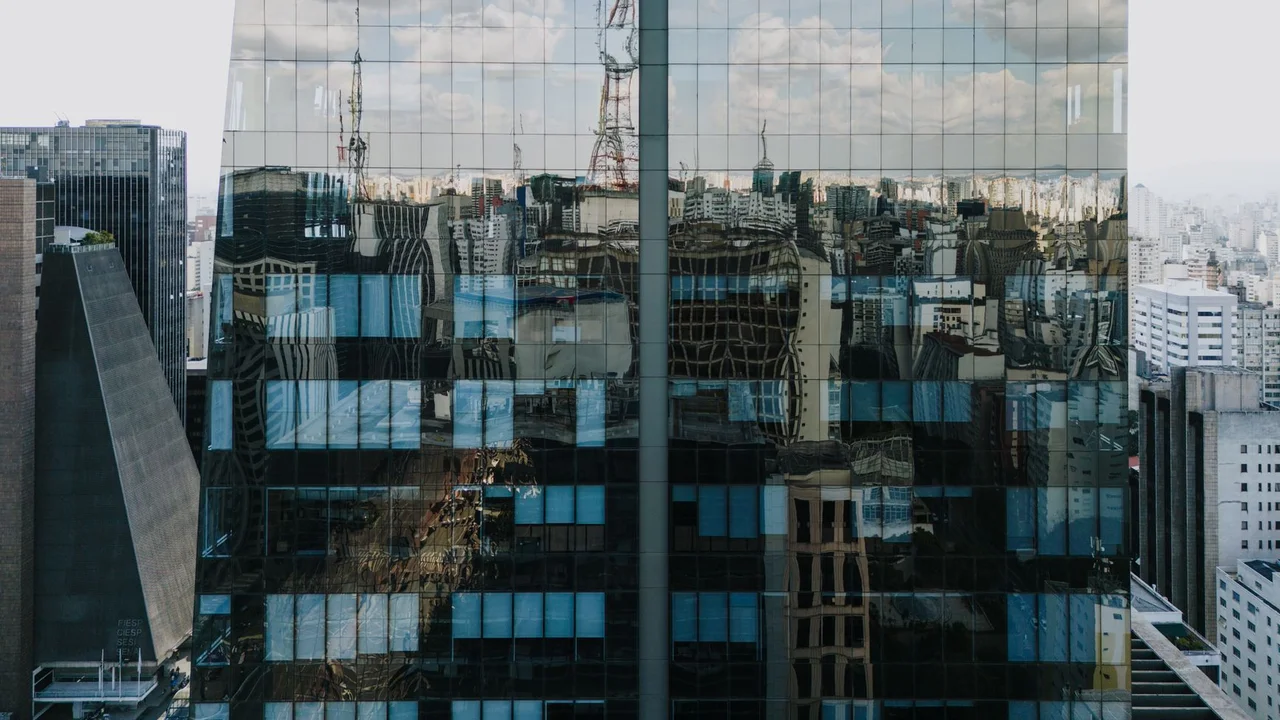 Reflection of São Paulo skyline on a modern skyscraper facade under a bright sky.