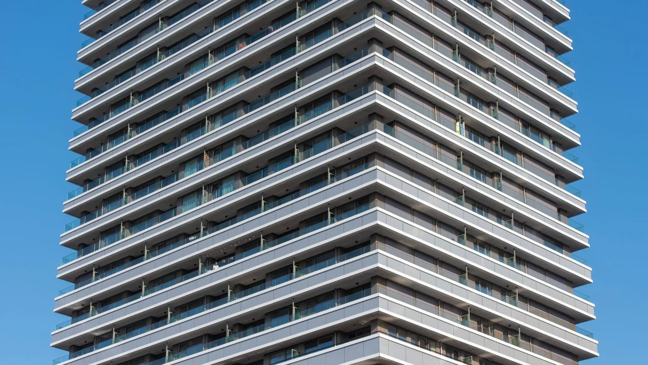 Close-up of a modern apartment high-rise building with clear blue sky background.