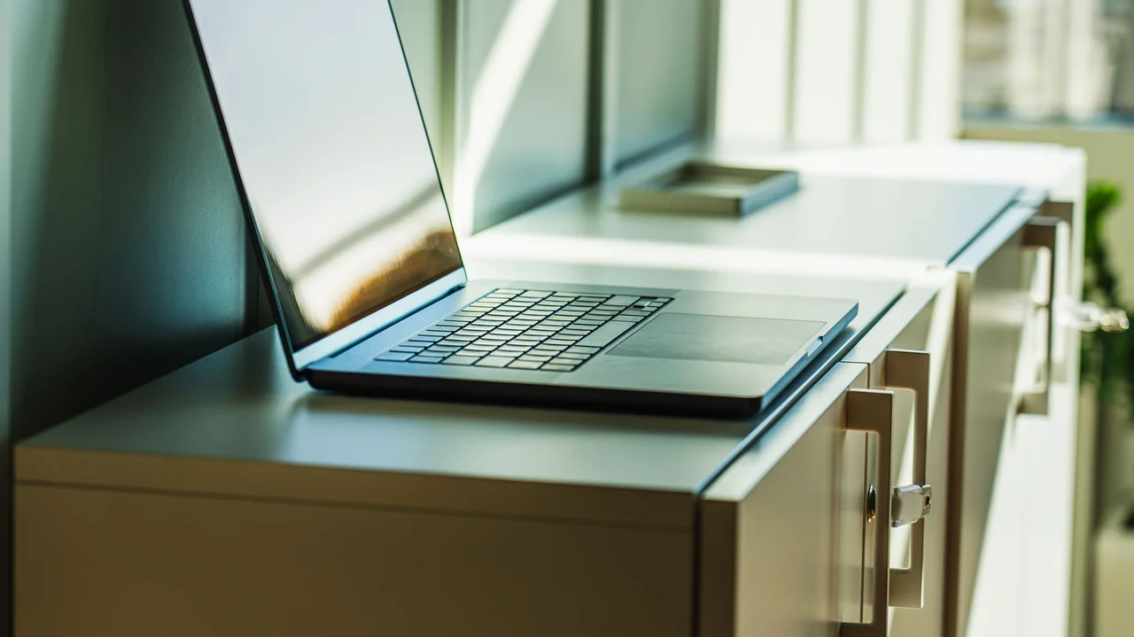 A laptop on a sunlit office cabinet, ideal for professional or corporate contexts.