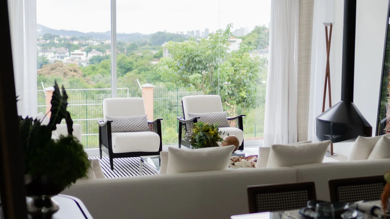 Elegant living room with modern decor, armchairs, and large windows offering a scenic view.
